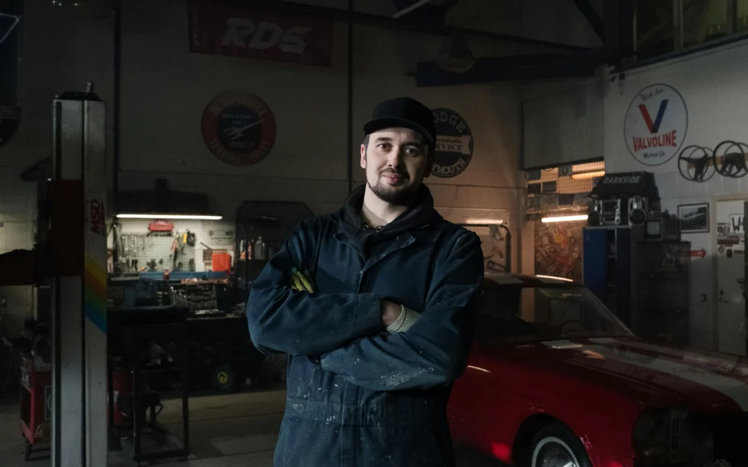 Mechanic standing in front of a car has a used engine for sale